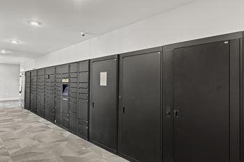 A row of black lockers in a room with white walls and a tile floor